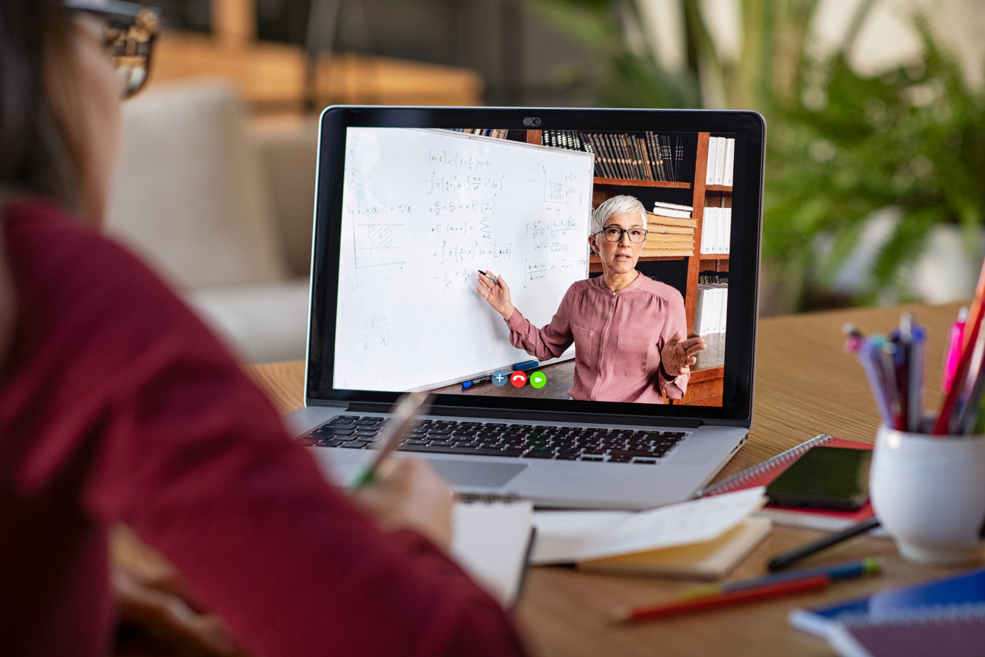 A student taking notes during an online class.